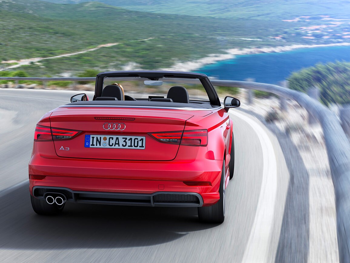 A red Audi A3 Cabriolet travelling a coastal route with the roof down