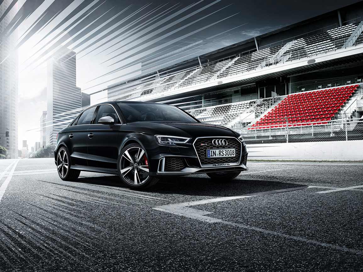 A black Audi RS 3 Saloon against a blended backdrop of a city and racetrack