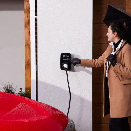 Woman charging her electric Audi with an Ohme home charger.