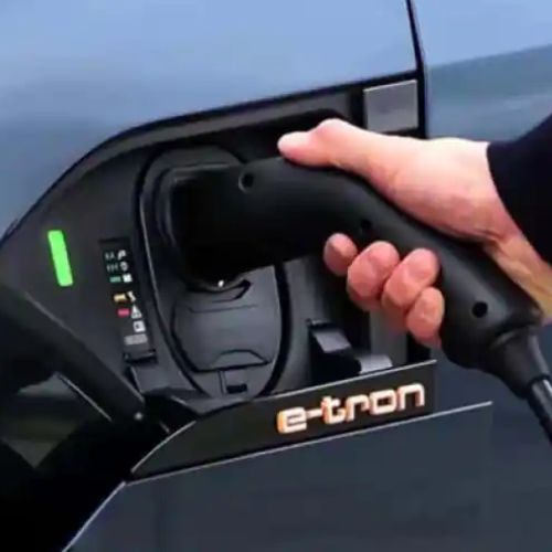 Hand plugging in charger to Audi e-tron car.