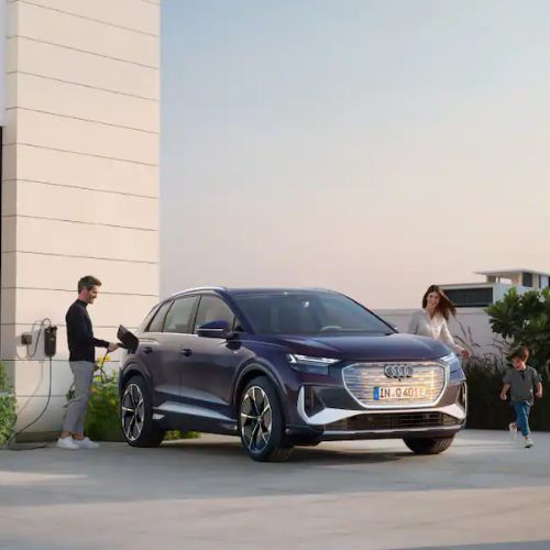 Man charging his Audi Q4 e-tron while a woman and child walk around the car.