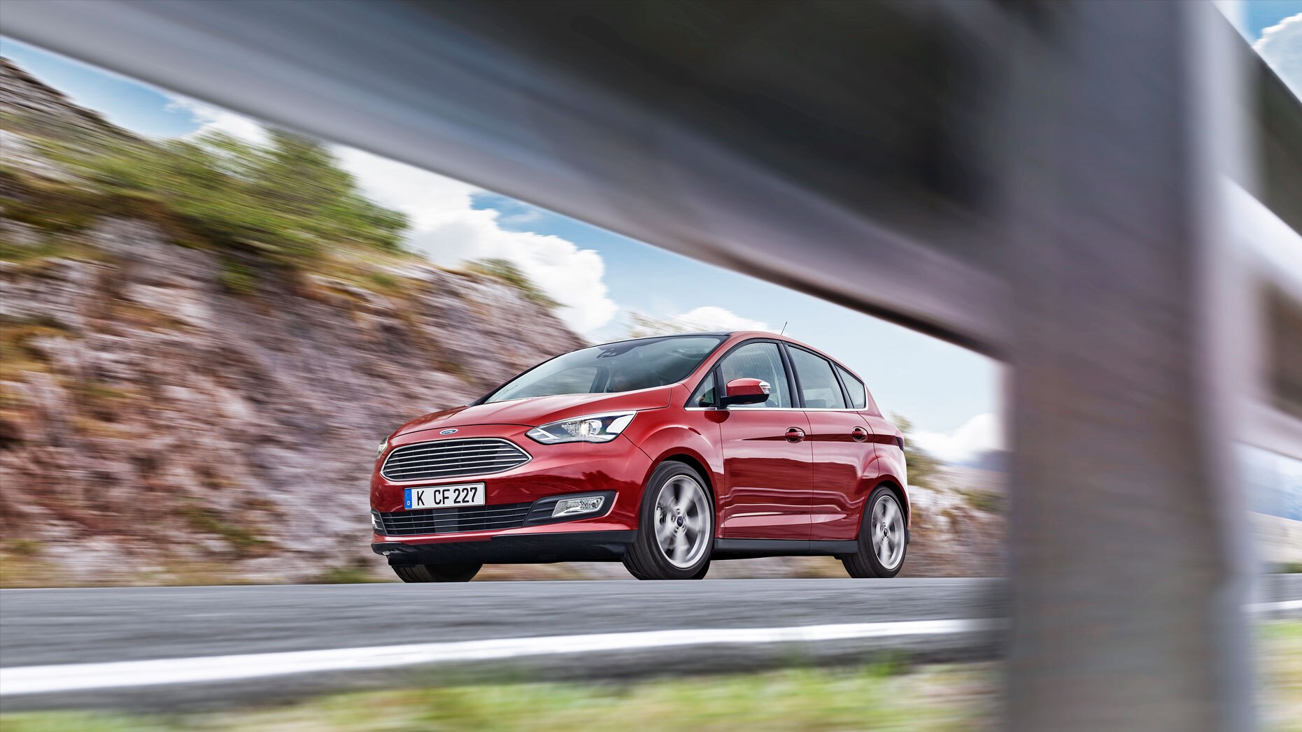 Used Ford C-MAX Header image featuring a front on photograph of a red Used Ford C-MAX driving on a country road.