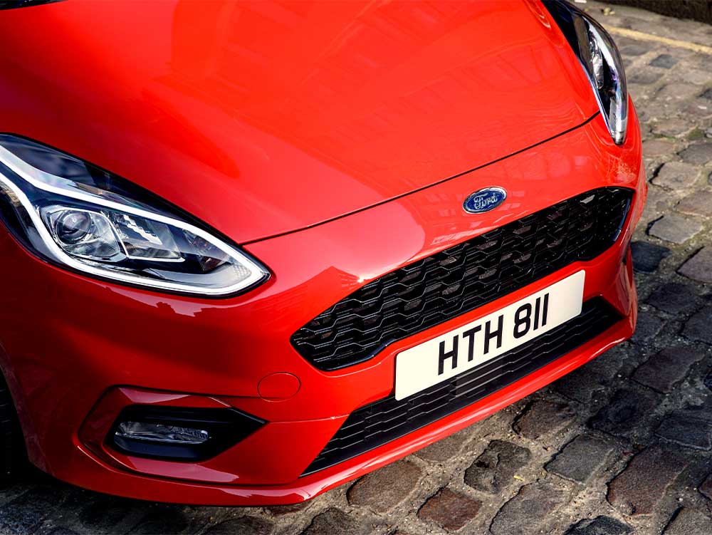 Used Ford Fiesta van Image Card featuring a red second hand ford fiesta van front grille shot.