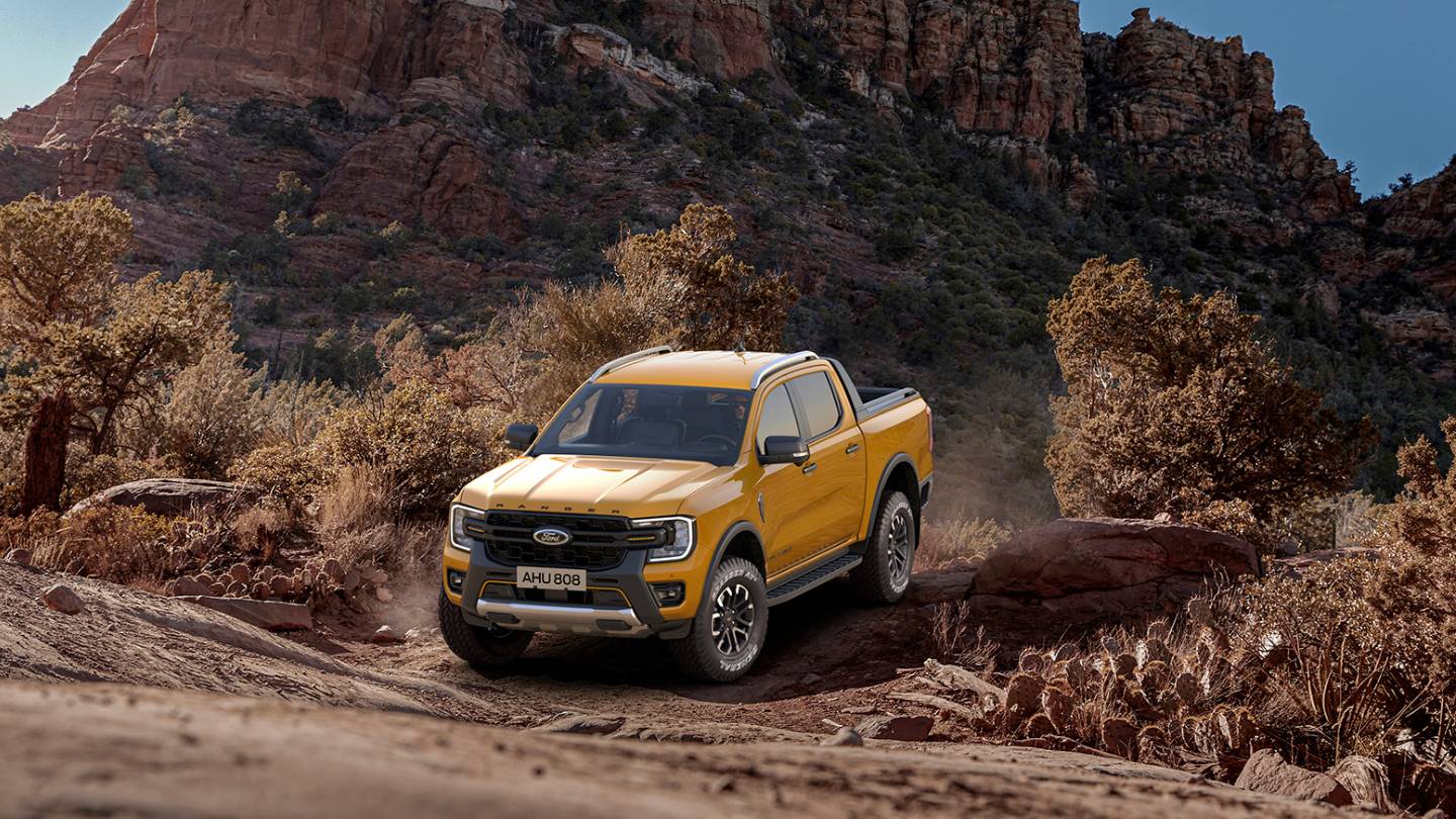 A yellow Ford Ranger Wildtrak driving through the rugged desert hills