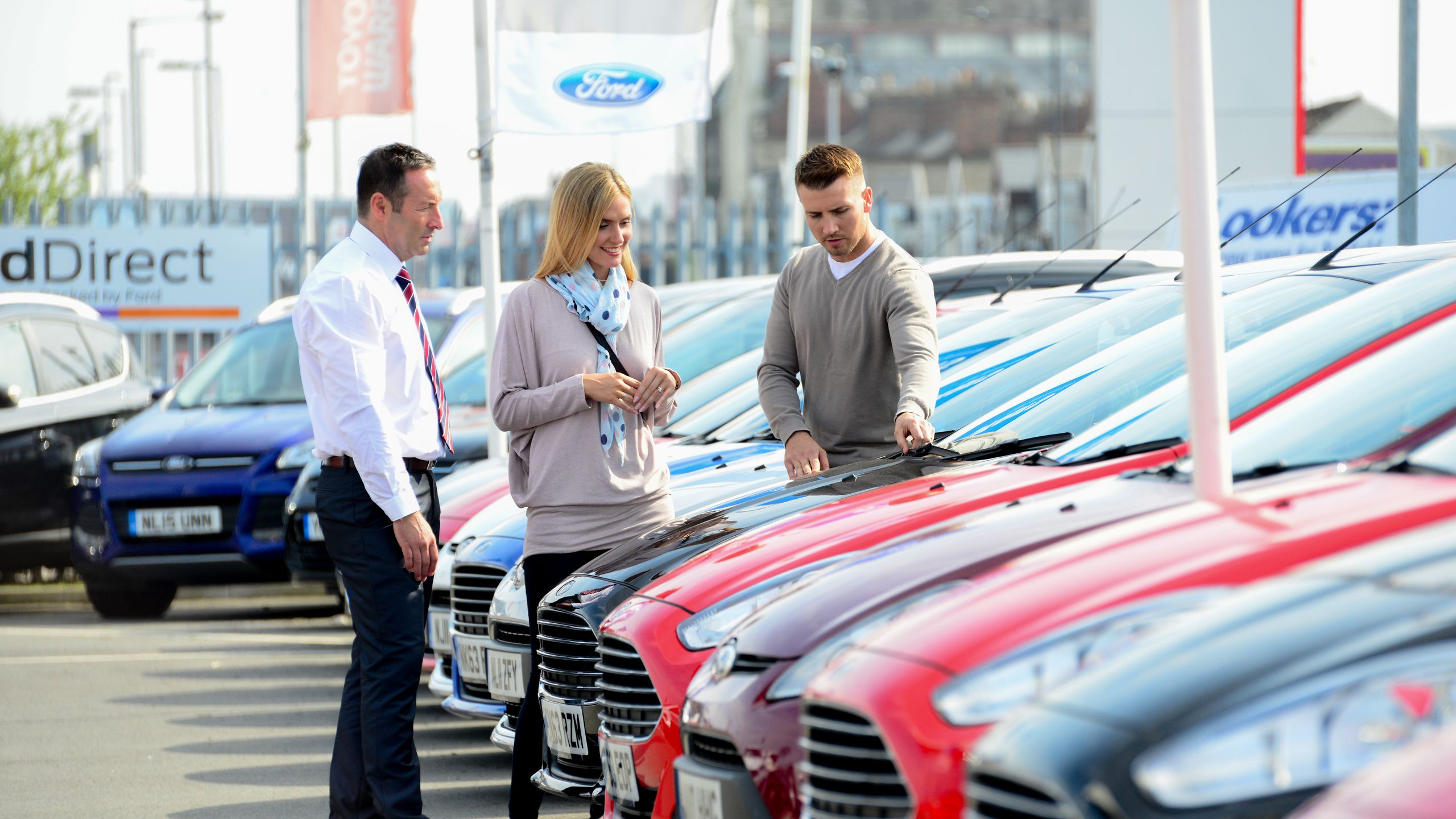 Used B-Max Header Image featuring a range of second hand Ford B-max cars in a Used Ford car park and two customers searching for sued ford b-max near me.