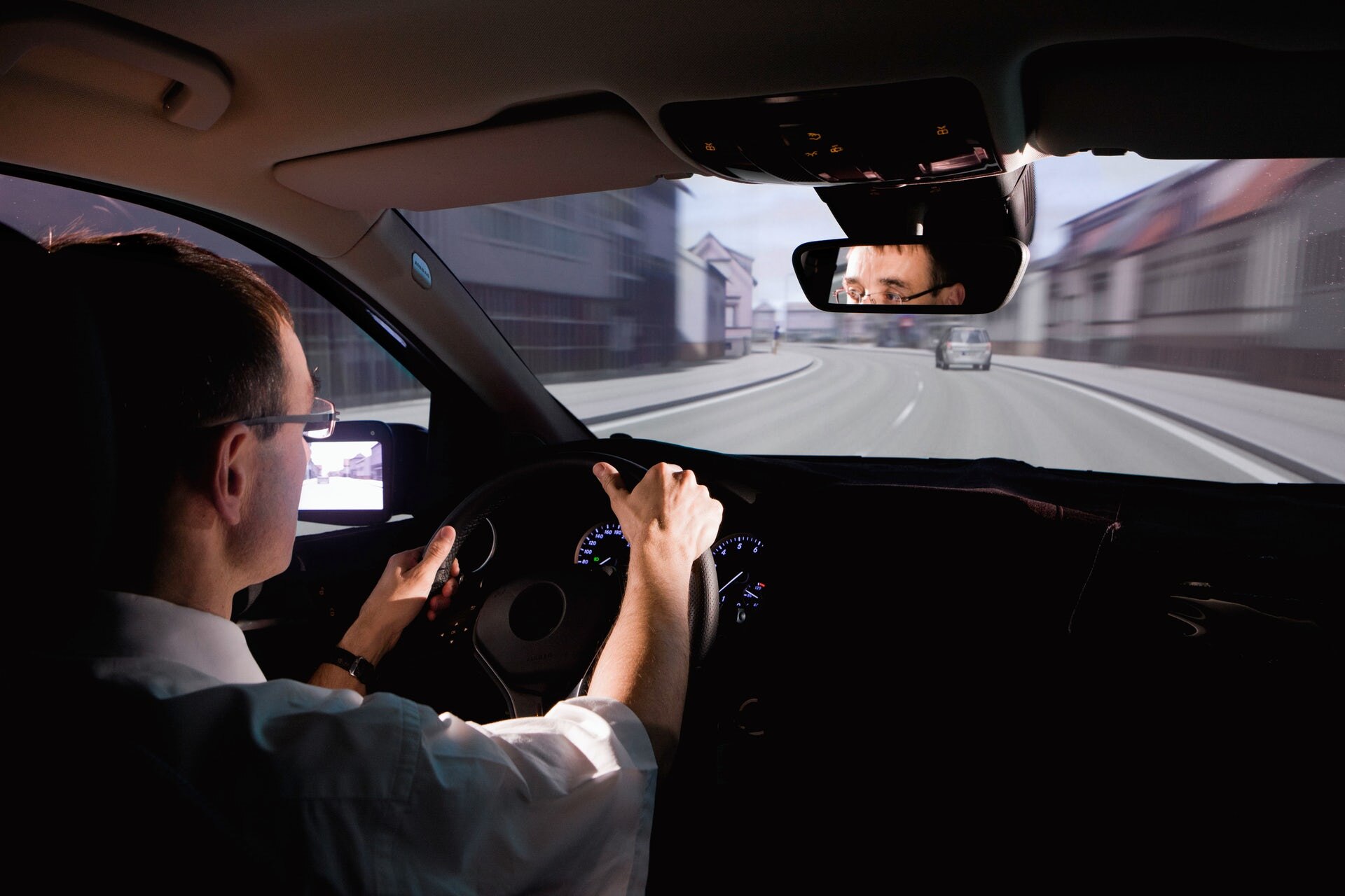 A man sitting at the wheel of a realistic driving simulator