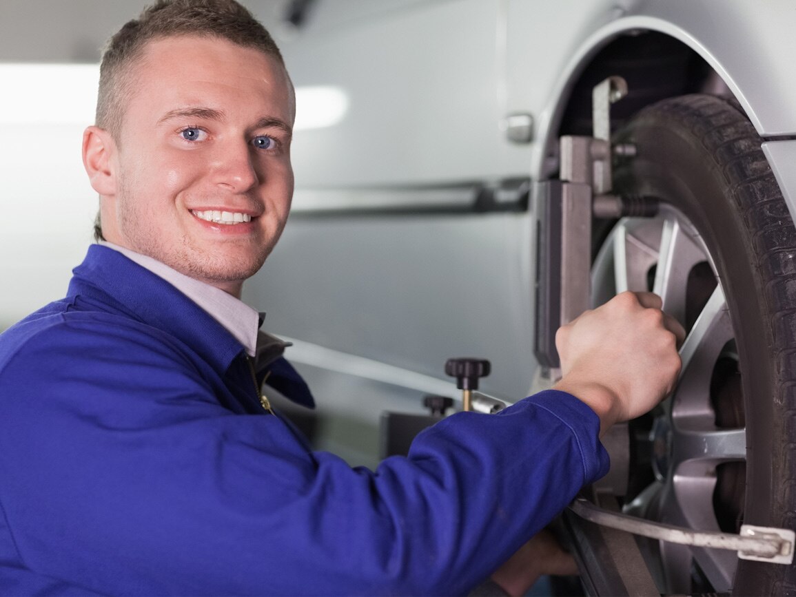 A technician working on a car's wheel and tyre