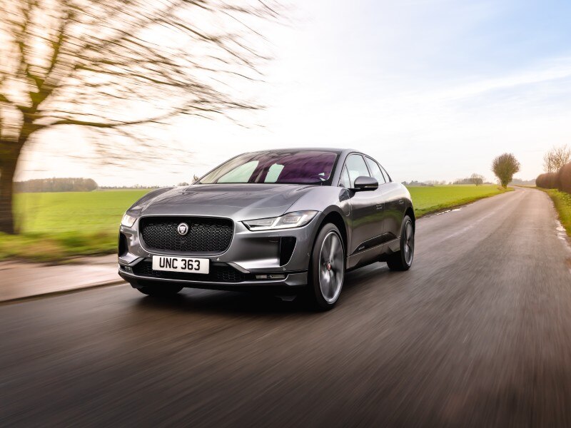 Battery Electric Vehicle BEV Image Card - Featuring a grey Jaguar I-PACE full electric car driving on a country road.