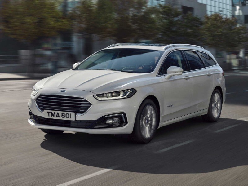 Hybrid Electric Vehicles Vehicle Types Image card - featuring an Hybrid Electric Ford Mondeo in white, side profile of the HEV driving in a city centre.