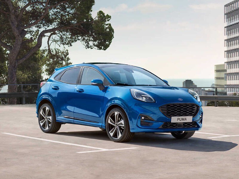 Mild Hybrid Electric Vehicles MHEVs Image Card - Featuring a side profile shot of a Blue Ford Puma Mild Hybrid vehicle Parked in a space in an empty car park. 