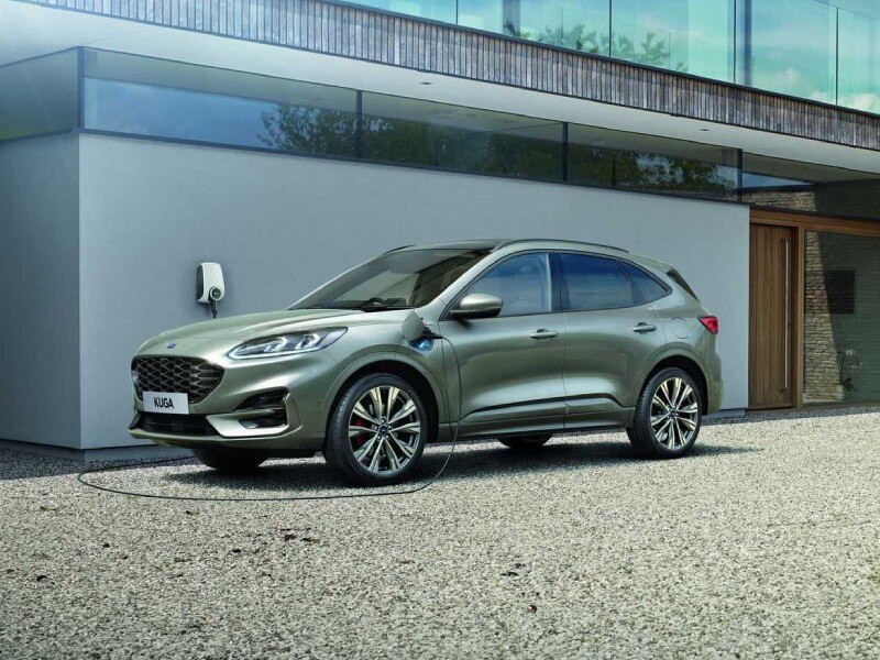 Plug-in Hybrid Electric Vehicle PHEVs image card featuring the backend of a Plug-in Hybrid Ford Kuga in grey parked outside a residential property charging in a wall box electric car charging point.