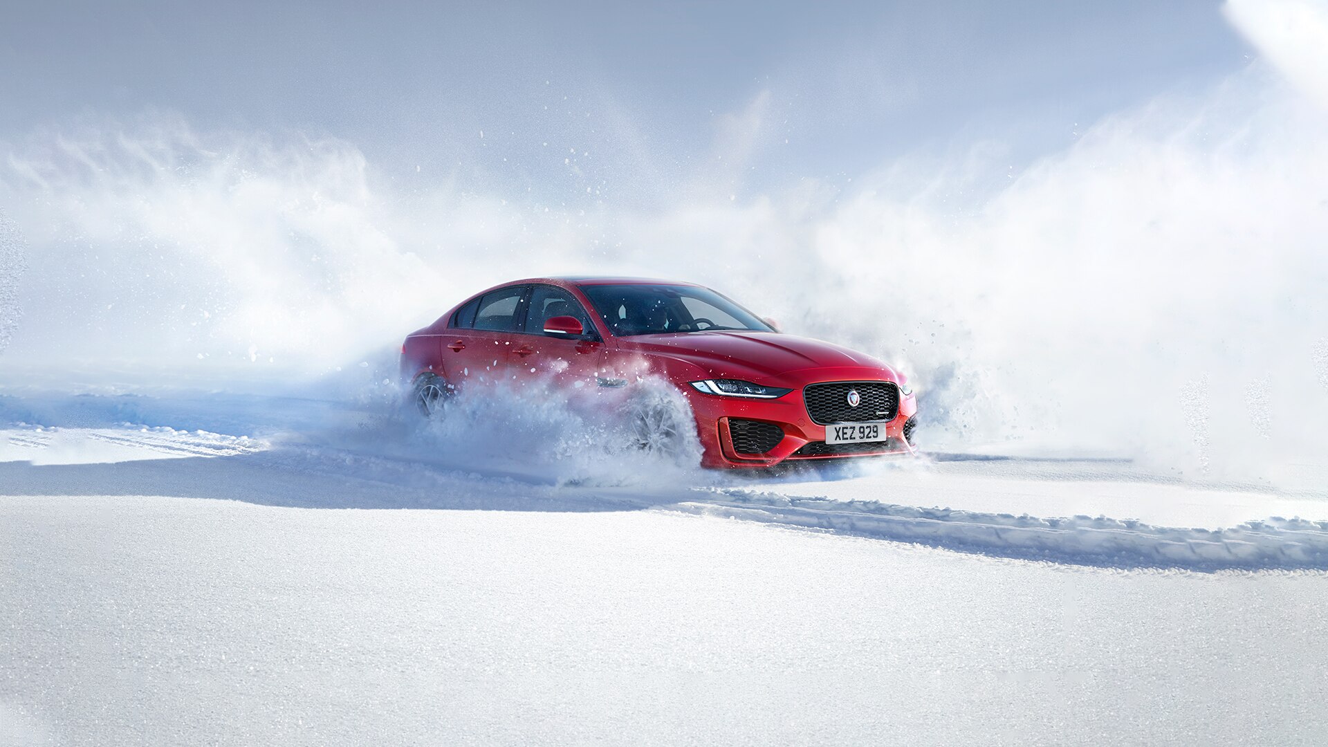 Lookers Jaguar Winter Driving Tips Car Advice Header Image. Showing a Red Jaguar XE Driving through Snow.
