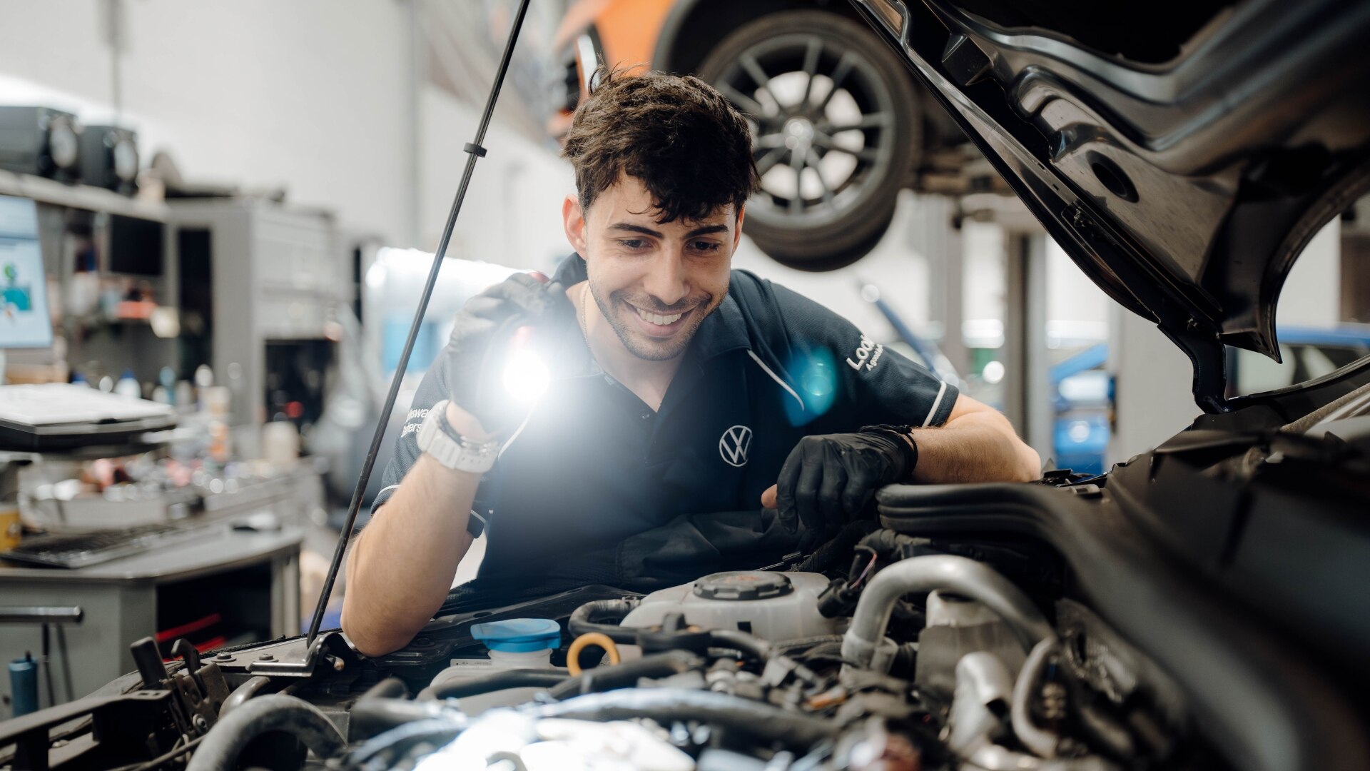 Volkswagen technician shining a torch into the engine of a car