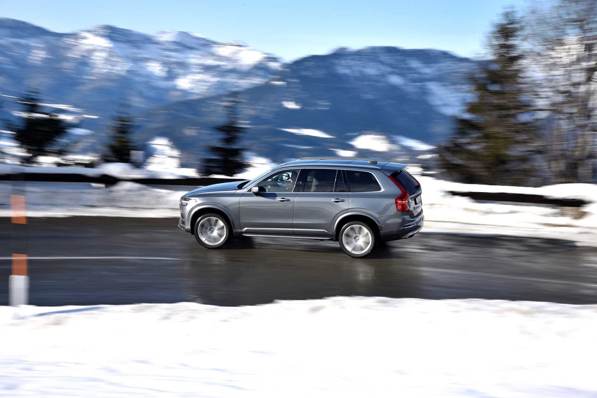 Lookers Volvo Winter Driving Tips Car Advice Header Image showing a Volvo XC 60 in grey driving on a wet road surrounded by snow in a mountain range.